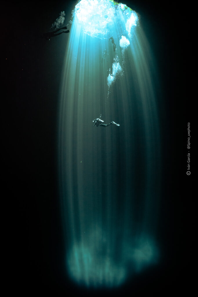 Triton Diving enthusiast gracefully descends in the serene light shaft of Cenote Maravilla