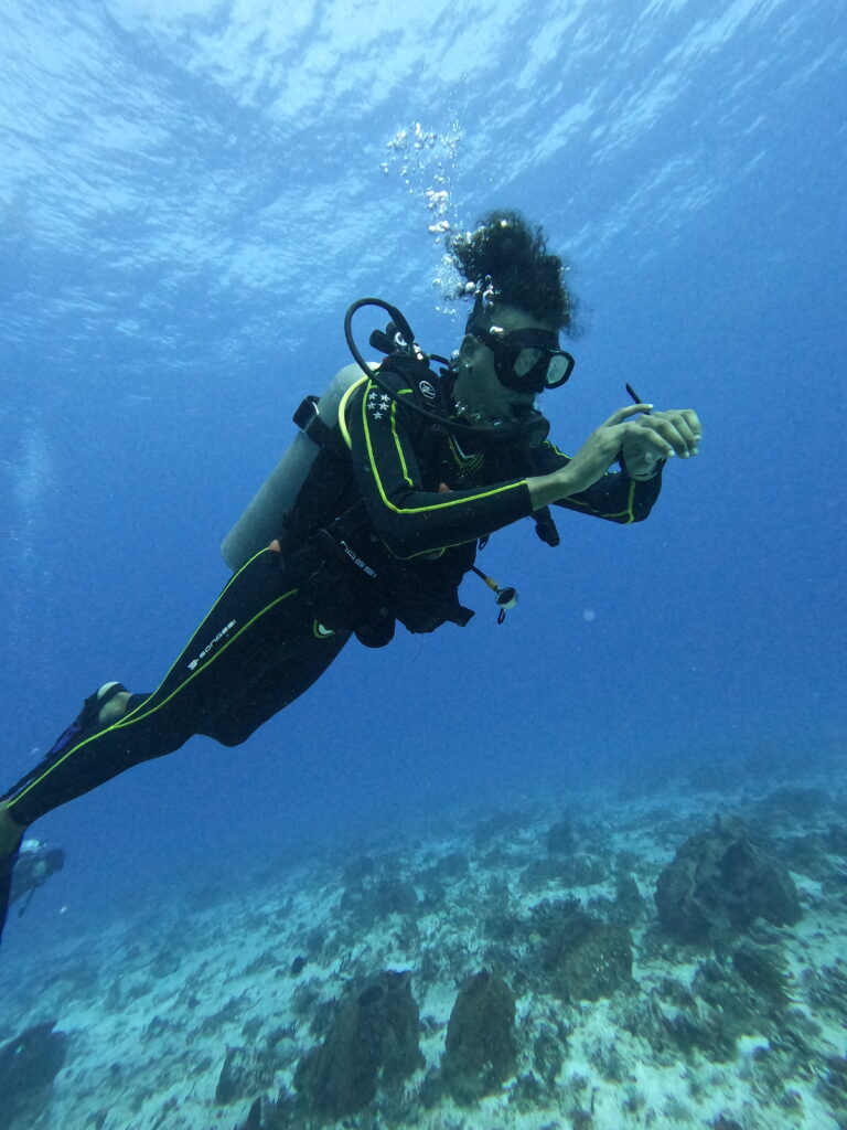 Triton Diving instructor during a PADI Open Water course in Playa del Carmen, attentively checking a dive computer for safety.