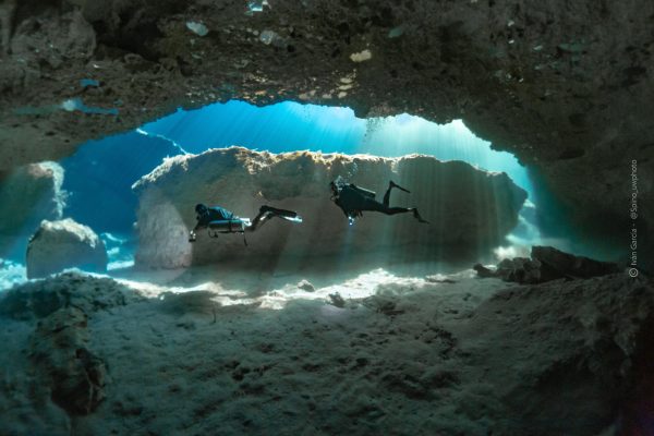 Silhouette de Triton Diving contre les rayons radieux du soleil perçant à travers l'eau de Casa Cenote